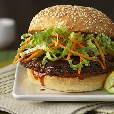 burger on seeded bun with lettuce and shaved carrots, cucumbers on the site