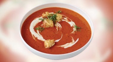 red pepper soup in a bowl with garnish