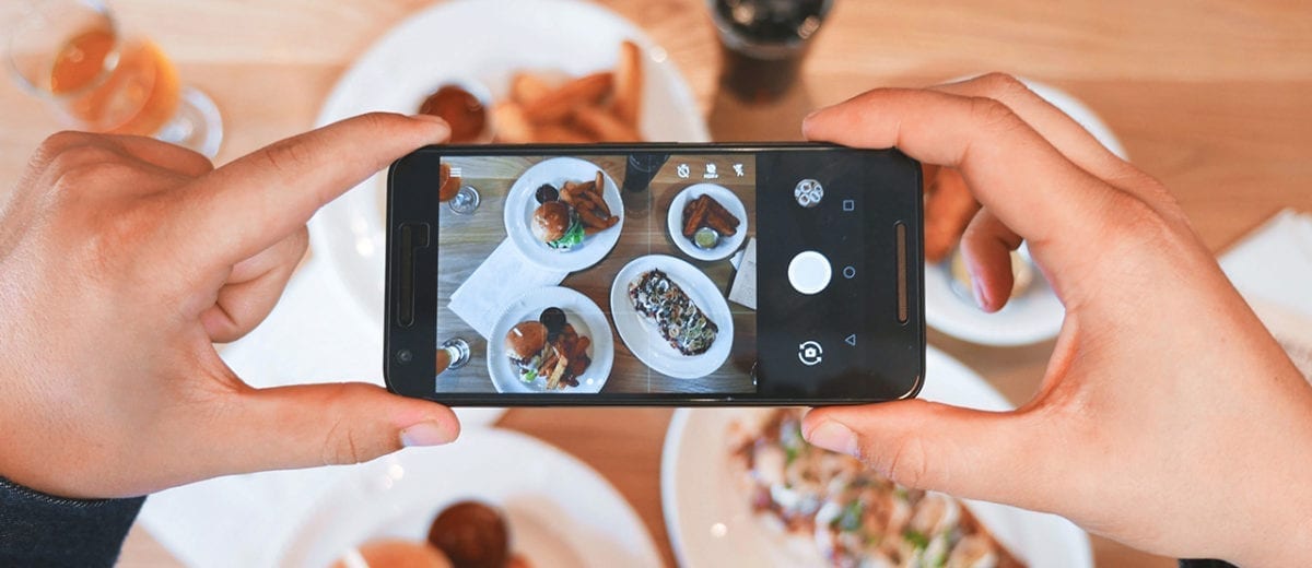 person holding smart phone taking photo of food