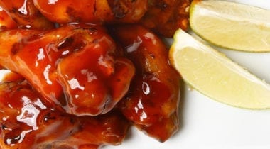 sauce coated chicken wings and lemon wedges