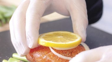 gloved hand placing lemon on food
