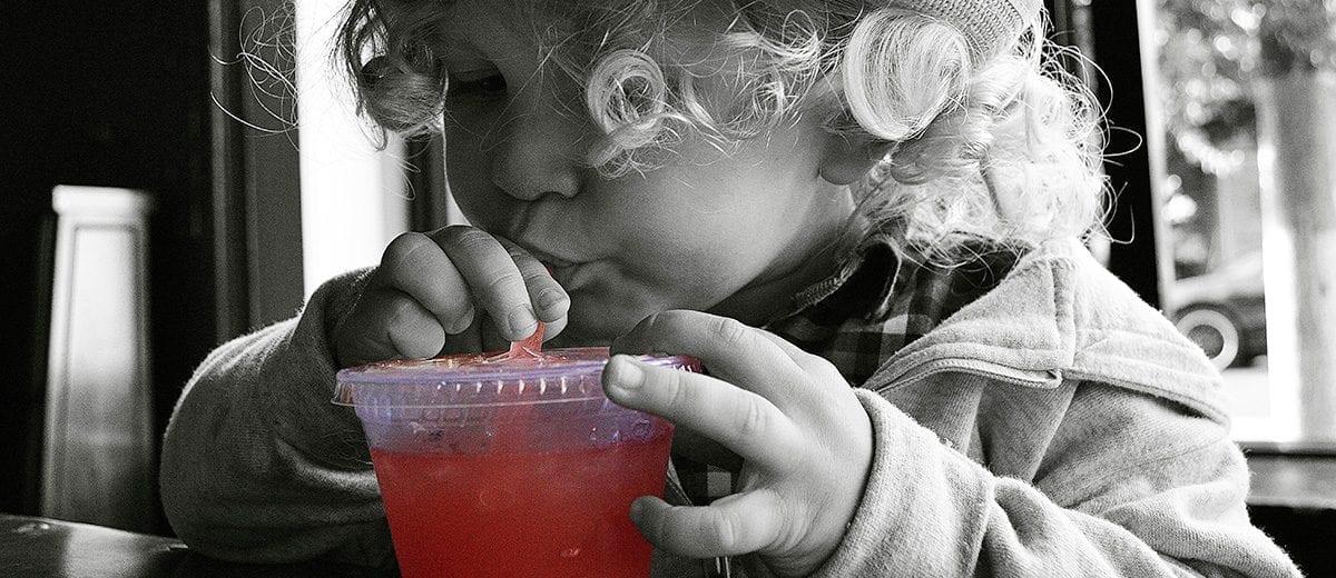 child sipping drink straw clear cup