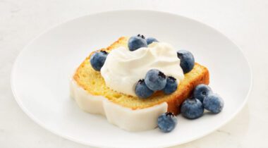 simple joys lemon cake slice on plate with whipped cream and blueberries